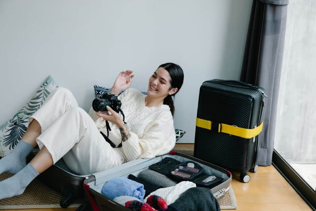 A Woman Sitting on a Luggage Holding a Camera