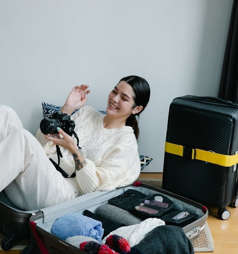 A Woman Sitting on a Luggage Holding a Camera
