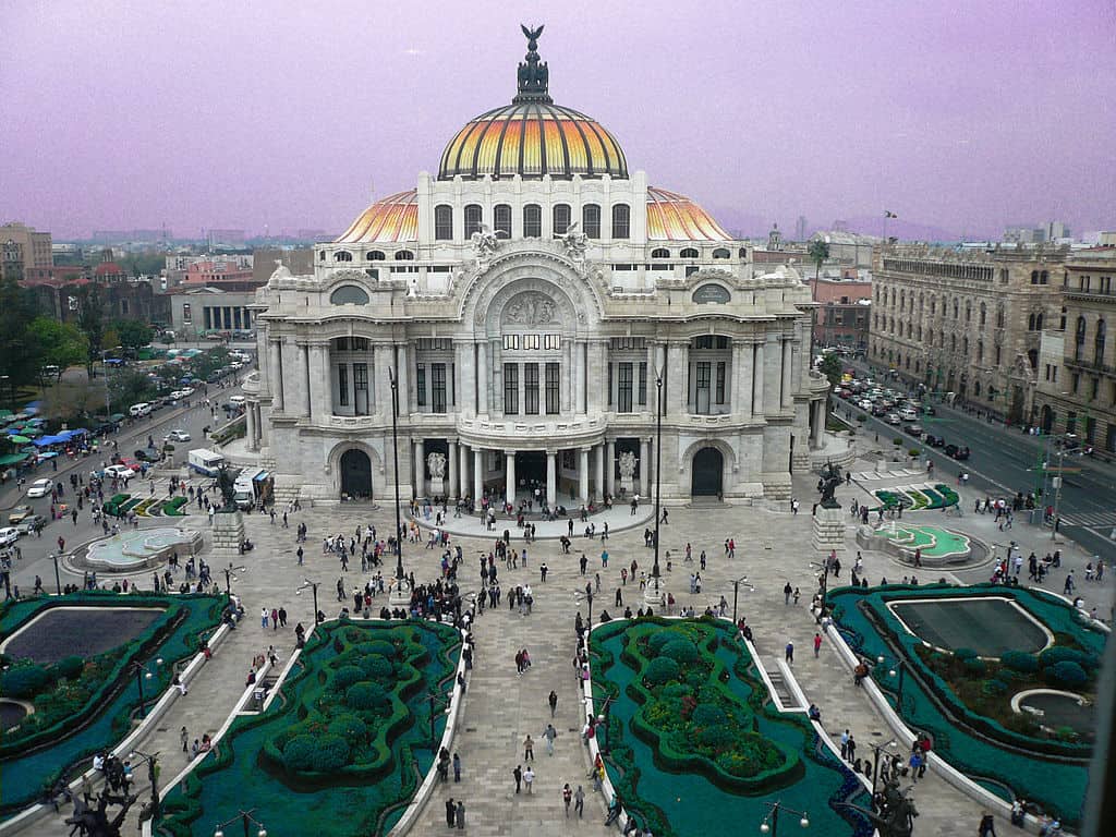 Majestic Palace of Fine Arts Mexico City with vibrant rooftop lighting at dusk.