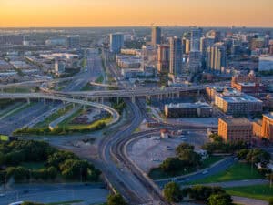 Experience a piece of American history with this stunning aerial view from the Reunion Tower of the Texas School Book Depository, the site where President John F. Kennedy was tragically assassinated in 1963. Captured from above, this image showcases the vibrant city of Dallas, Texas, with its bustling highways and towering skyscrapers, offering a unique perspective of this historical location. The composition of this photograph provides a powerful visual representation of the intersection of history and modern urbanization, making it the perfect addition to any editorial, documentary or news project.