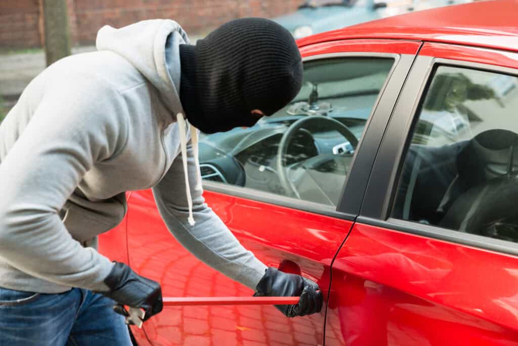 thief opening car door at red light urban street
