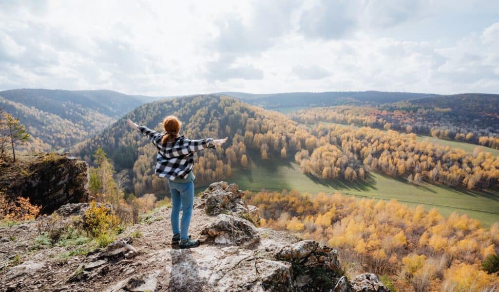 Girl standing on the edge of the mountain and enjoying the sun relaxing in the mountains hiking in nature high quality photo