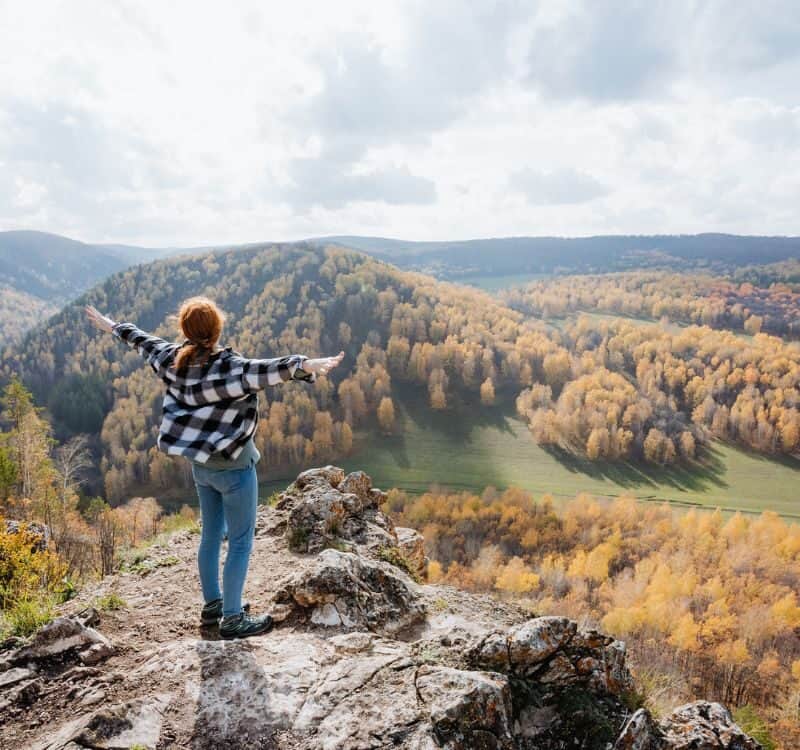 Girl standing on the edge of the mountain and enjoying the sun relaxing in the mountains hiking in nature high quality photo