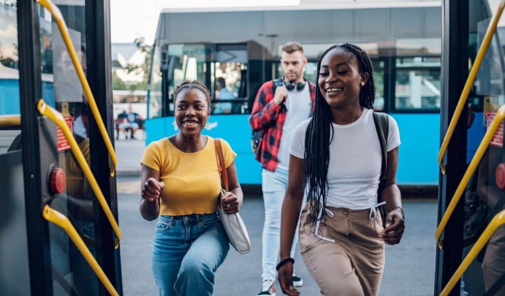 Multiracial young friends entering the public transport in the city