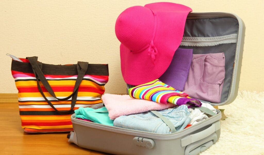 Open silver suitcase with clothing in room