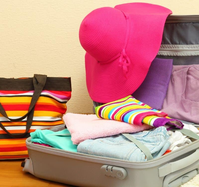 Open silver suitcase with clothing in room