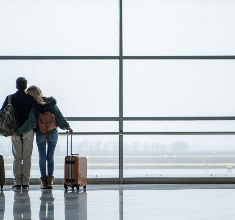 Two young people embracing while looking at the beautiful view from the airport window. Copy space in right side