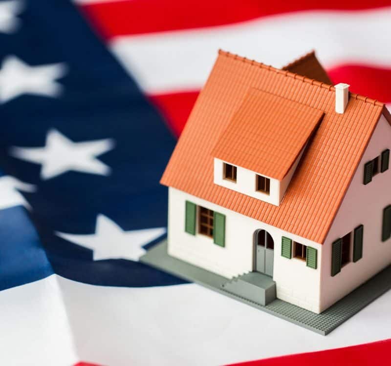 citizenship, residence, property, real estate and people concept - close up of living house model over american flag