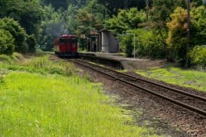 Red scenic train on lush forested railway track in Oregon.