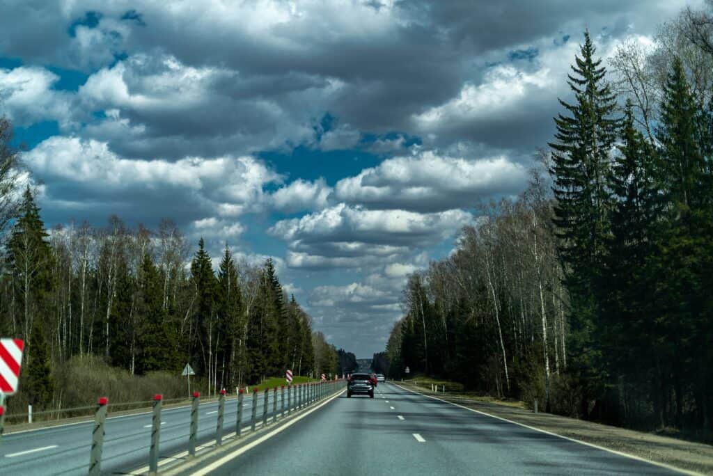 car driving under cloudy sky long empty road