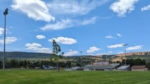 Outdoor sports stadium with lush green fields and scenic mountain views. Ideal for community events and athletic activities.