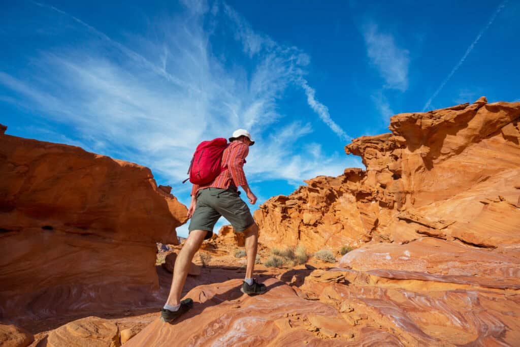 hiker walking desert canyon midday heat shimmering rocks”