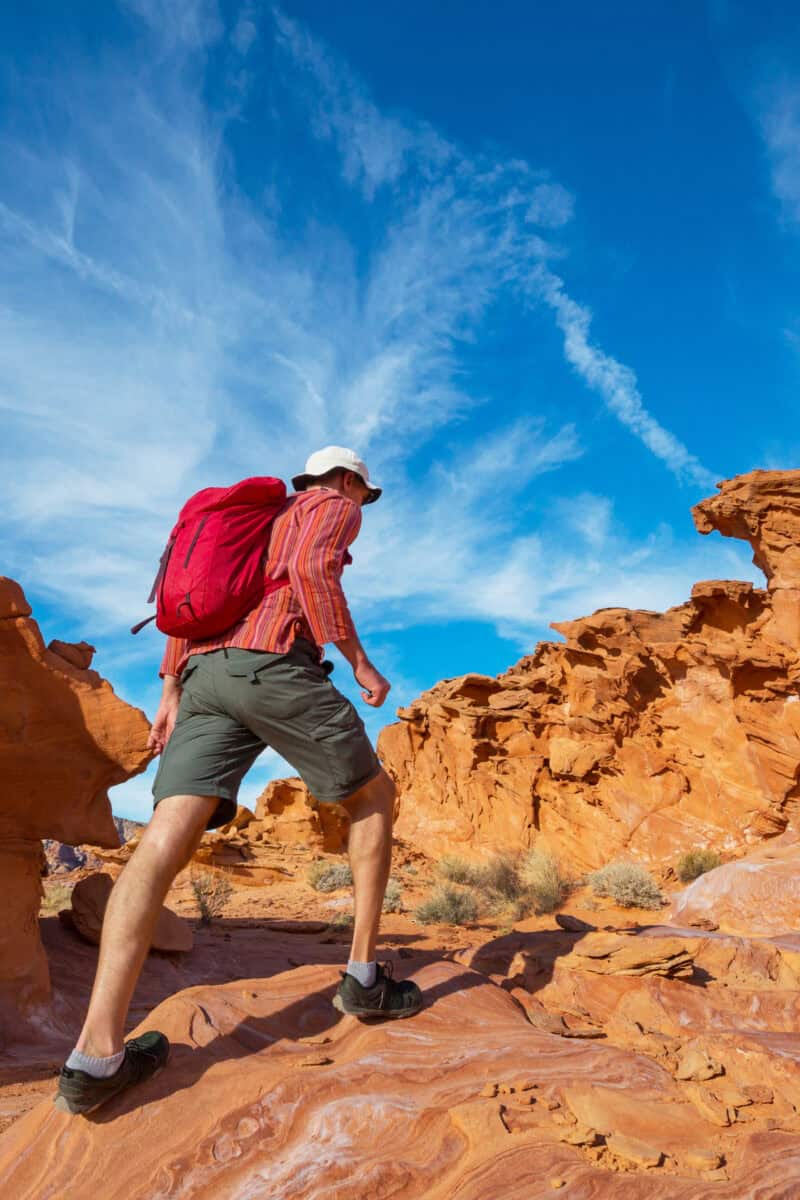 hiker walking desert canyon midday heat shimmering rocks”