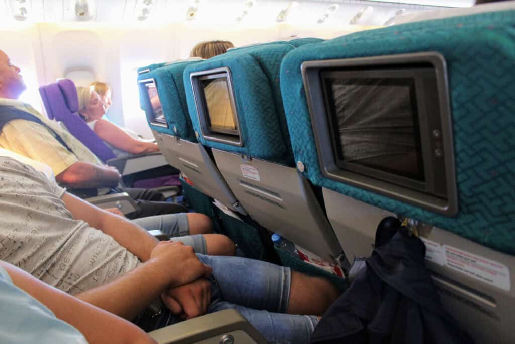 economy class airplane seat cramped knees touching seat in cabin