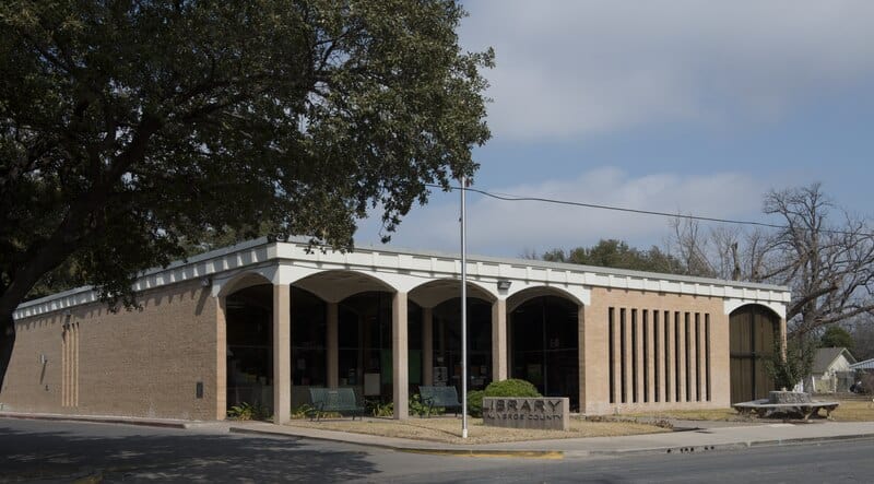 Bright, inviting library building with unique architectural design and greenery in a peaceful community setting.