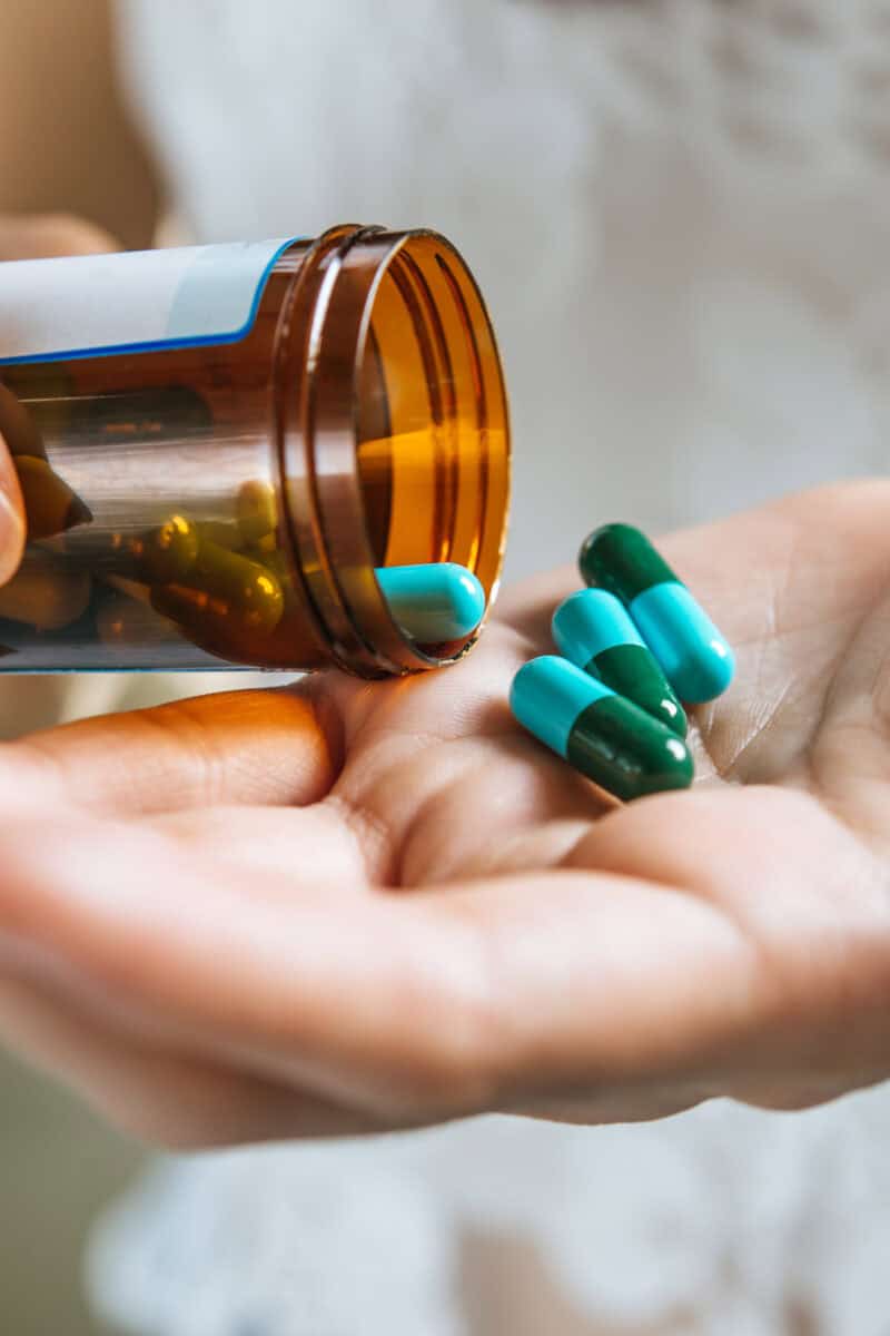 Woman's hand pours the medicine pills out of the bottle
