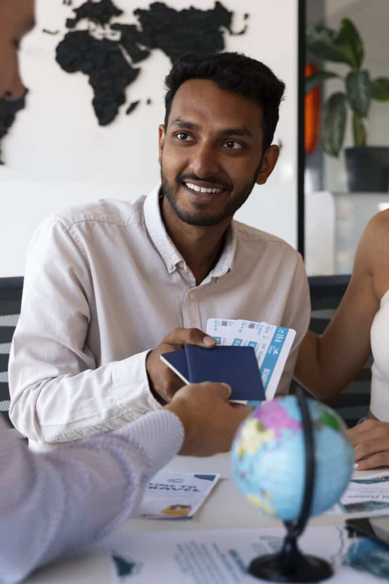 Travel agent giving tickets to young happy couple. Photo of female travel agent and young couple