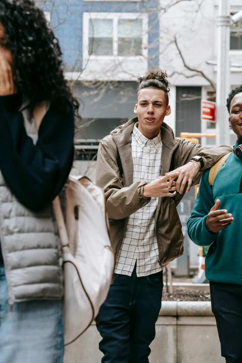 Young diverse men harassing female on street