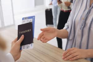 Agent giving passport with ticket to client at check-in desk in airport, closeup