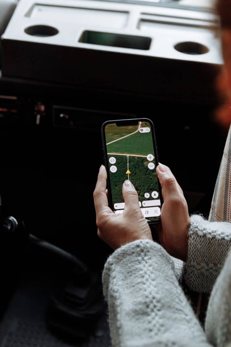 Two people using a navigation app on a smartphone during a road trip