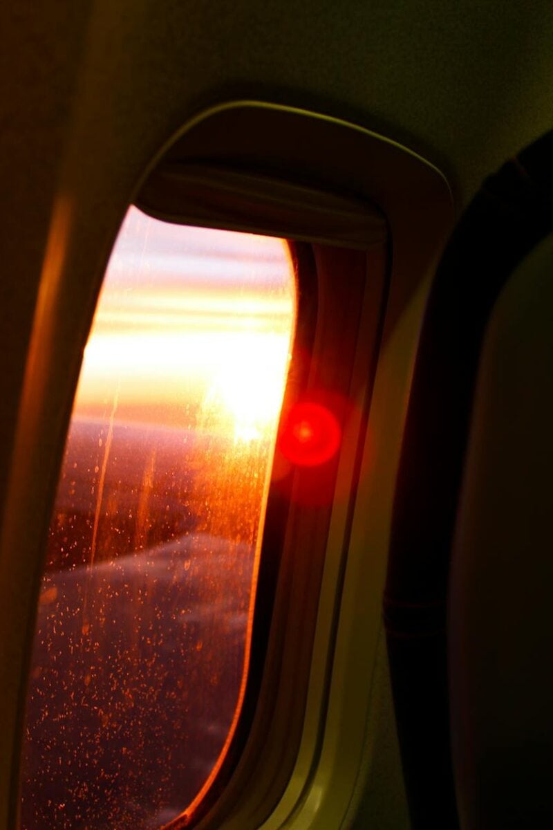 A stunning sunset view from an airplane window showcasing vivid skies and glowing horizon.