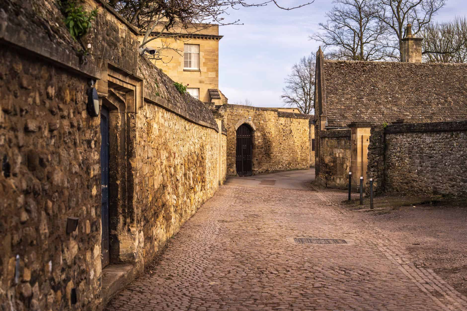 A rustic stone alleyway in historic setting, featuring cobblestone path and classic architecture.