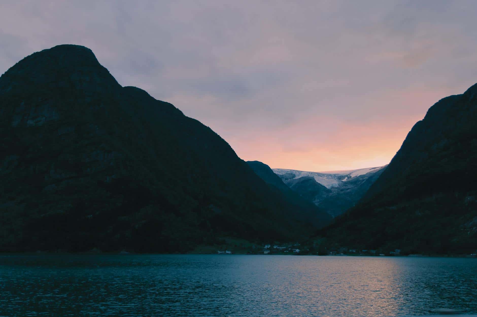 Breathtaking view of a fjord in Norway at sunset, framed by dramatic mountains.