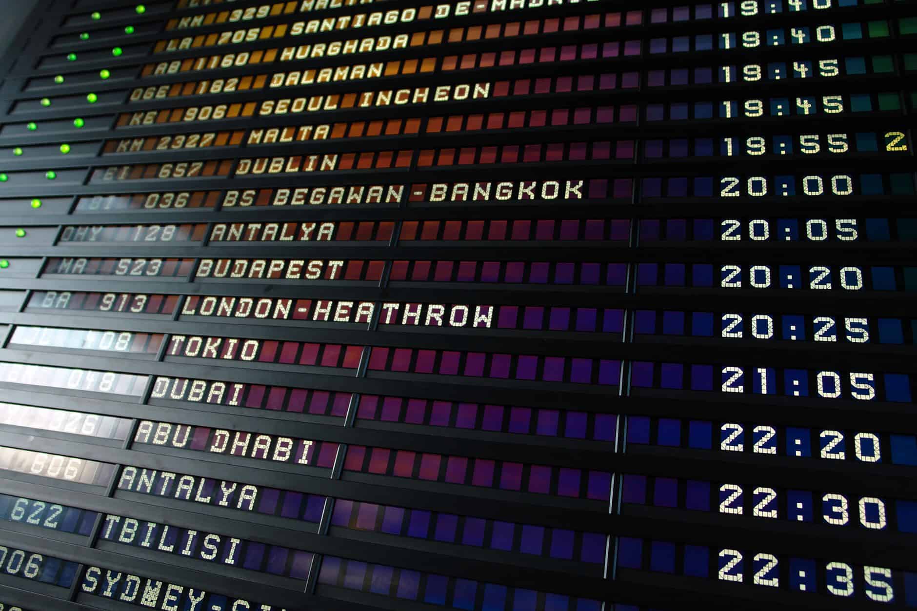 Retro flip-style airport departure board showing international flight destinations and times.