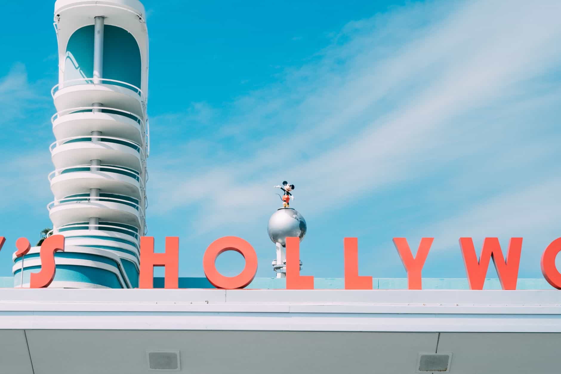 Vibrant photo of Disney's Hollywood Studios sign featuring a Mickey Mouse statue against a clear blue sky.