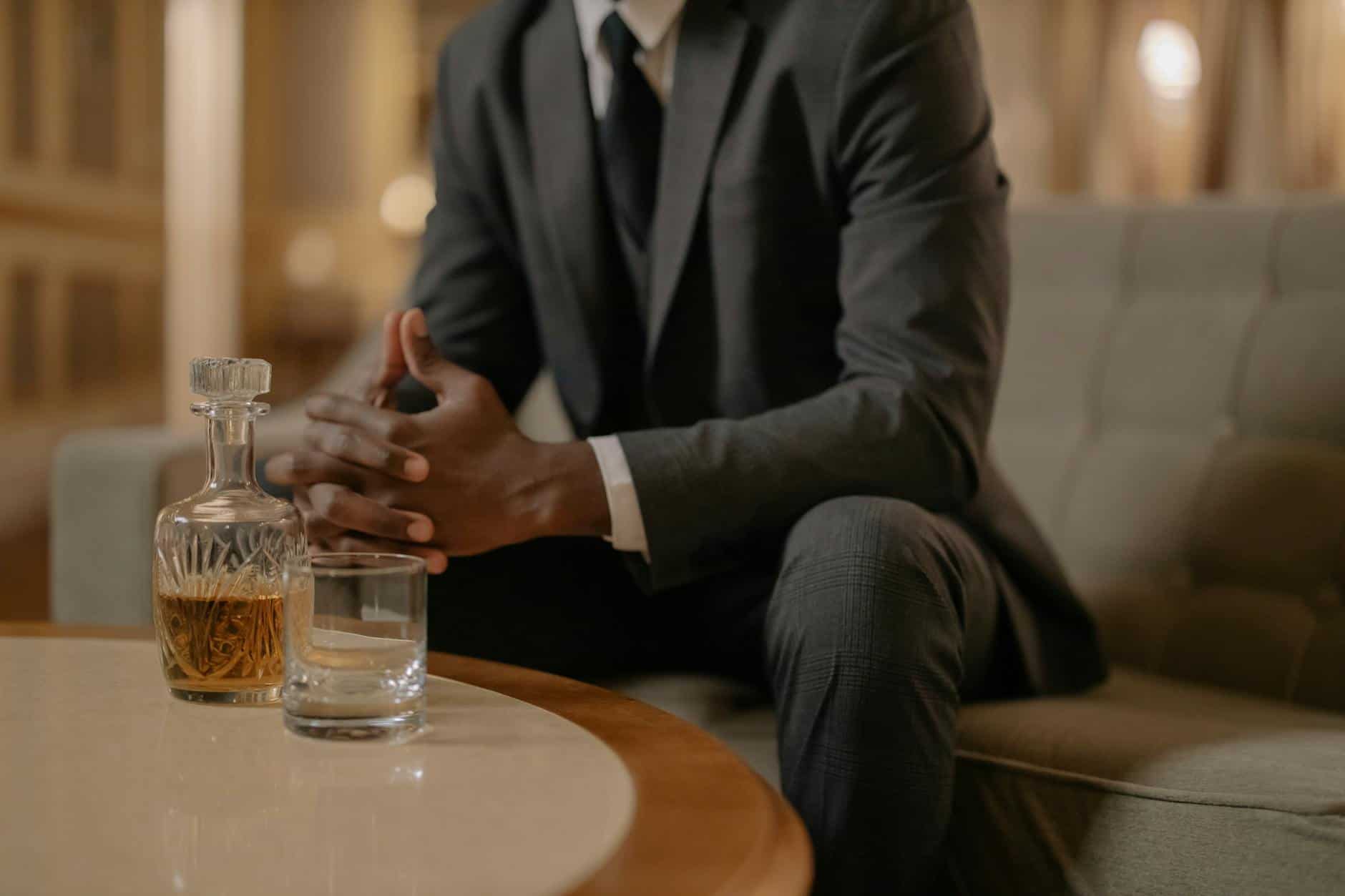 Sophisticated man in a suit enjoys whiskey in a luxurious hotel setting.