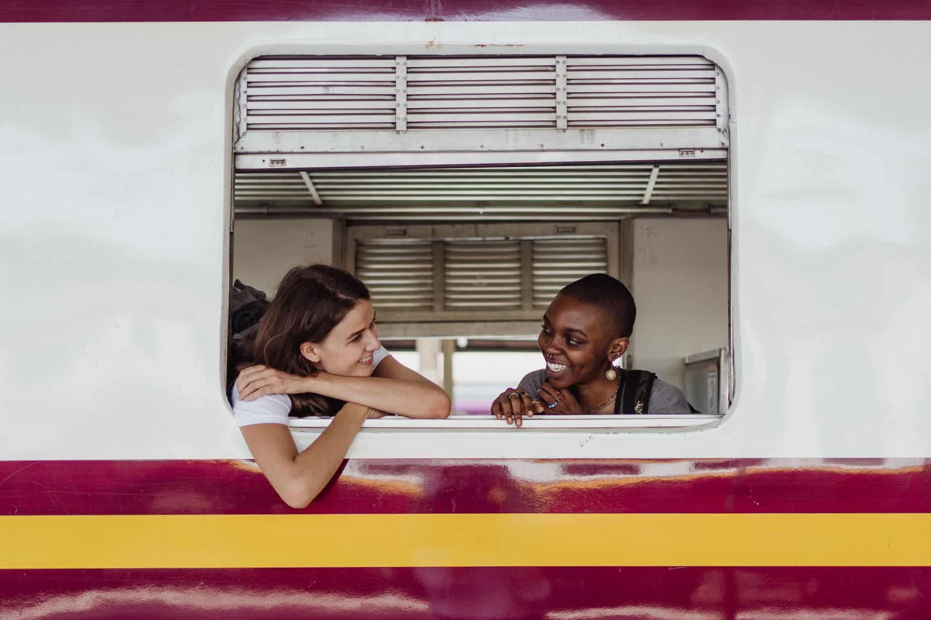Two smiling women enjoying a train ride, capturing a moment of friendship and travel.