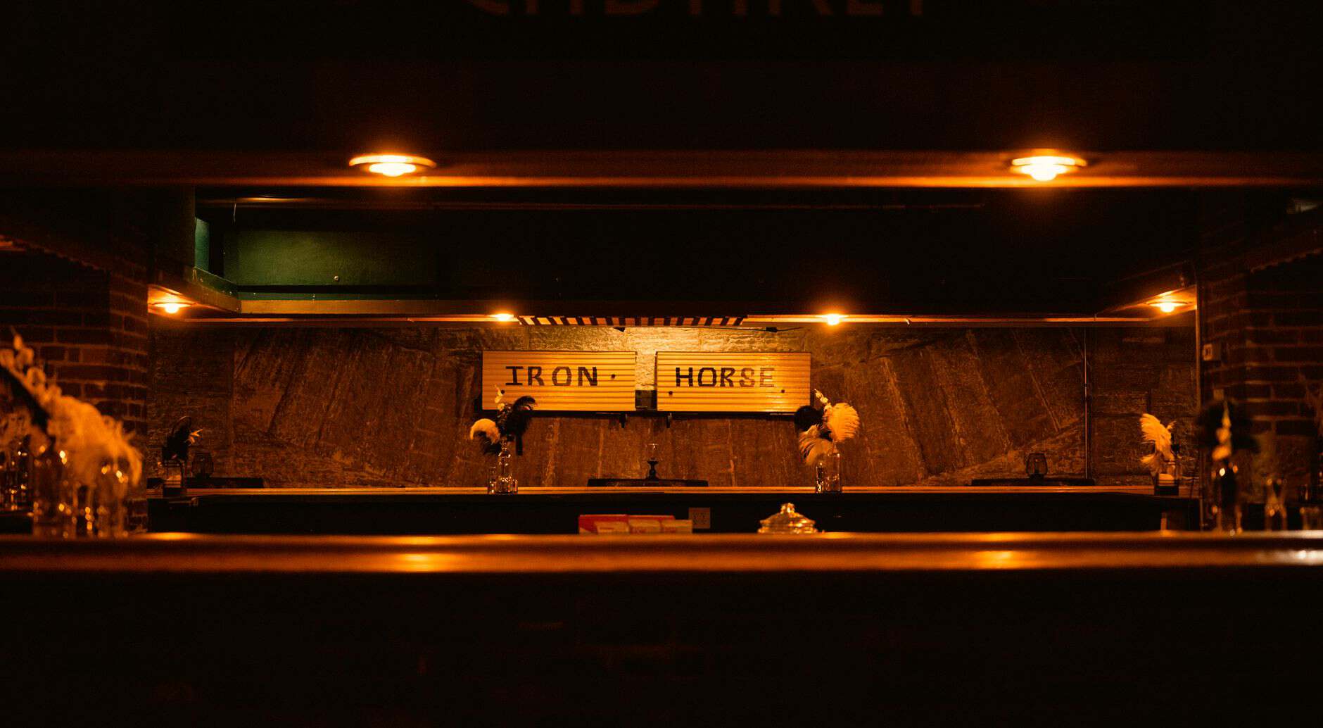 A warmly lit and empty bar counter at night displaying the name Iron Horse.