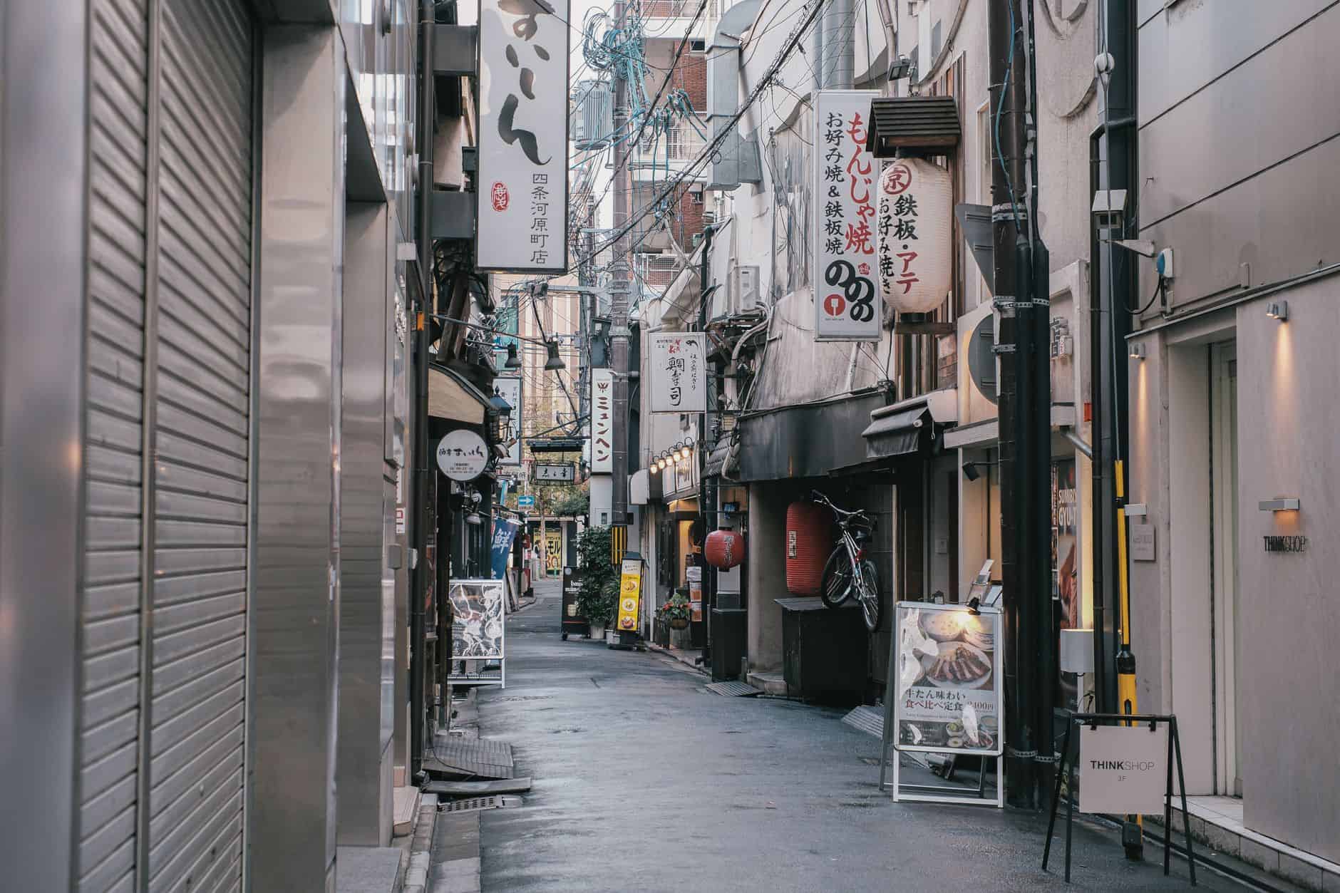 Capture of a quiet, narrow street in Tokyo, showcasing traditional Japanese architecture and vibrant signage.