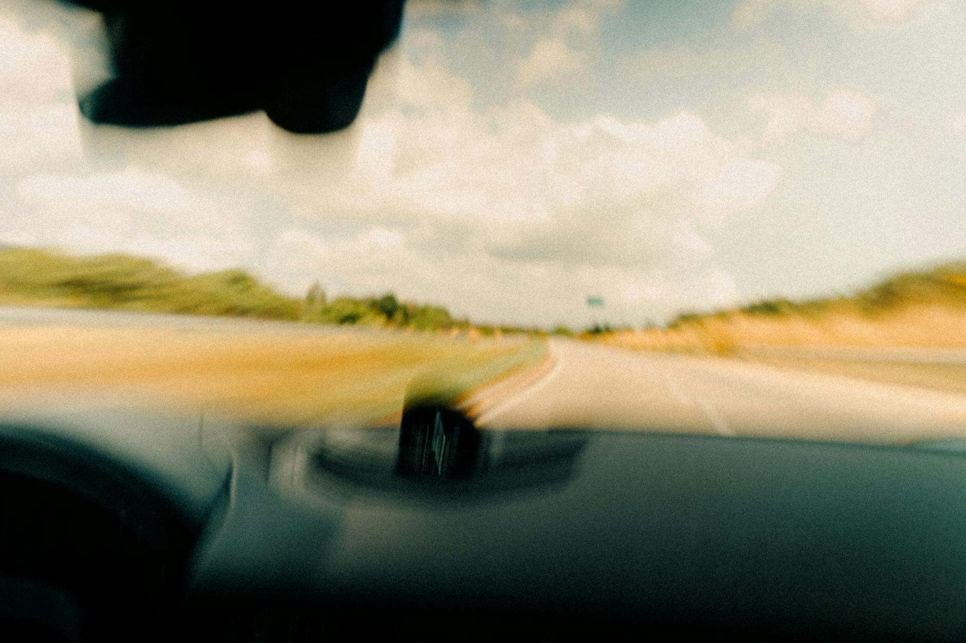 Dynamic blurred image from a vehicle's windshield capturing a rural road in motion.