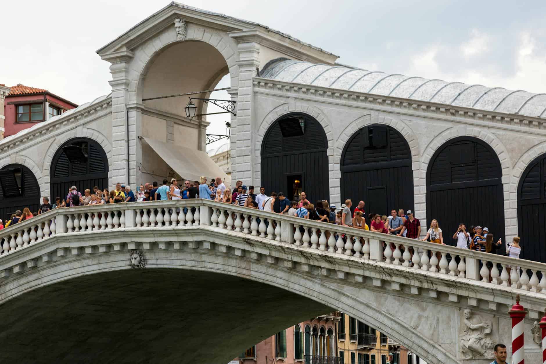 Tourists enjoy the view from the historic Rialto Bridge in Venice, Italy.