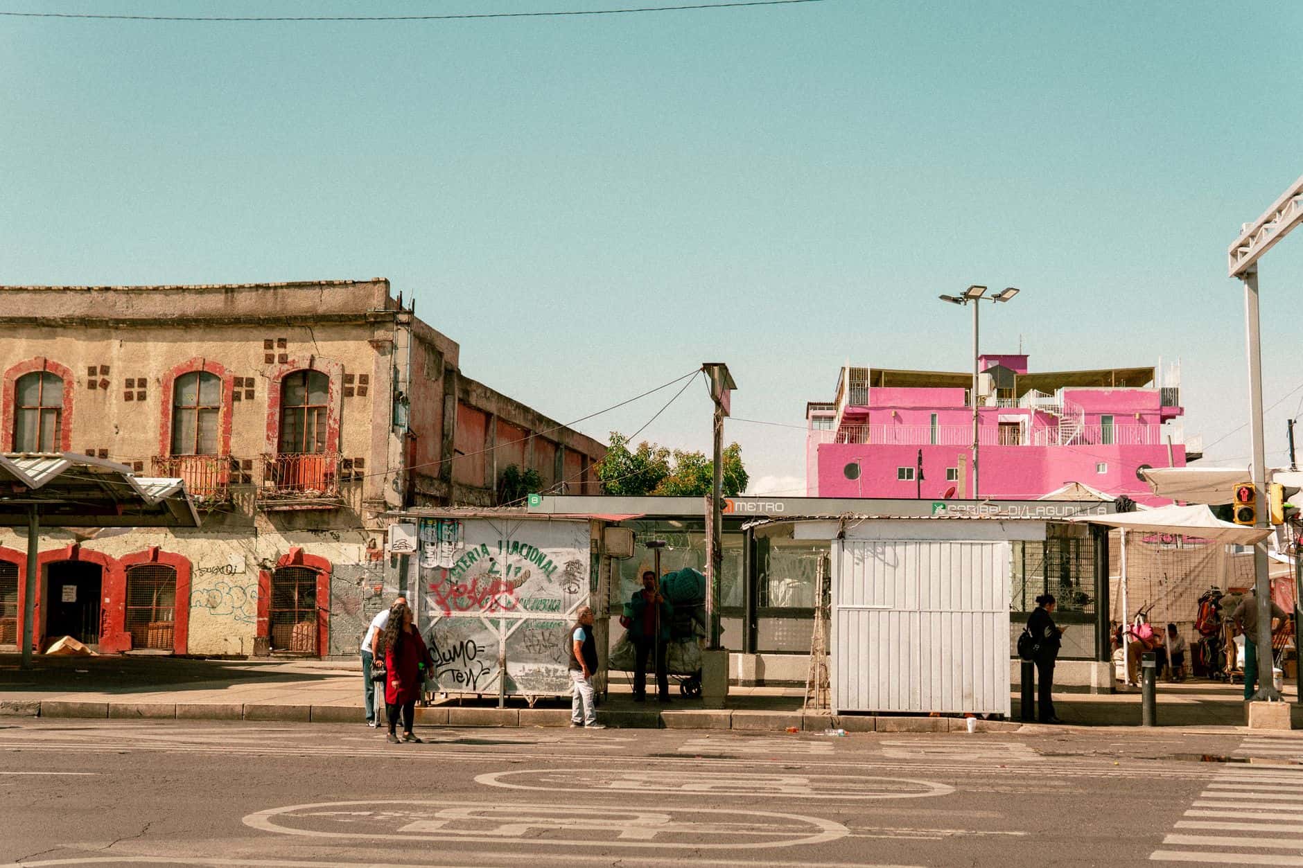 Bus stop scene with colorful buildings in Ciudad de México, showcasing local urban life.
