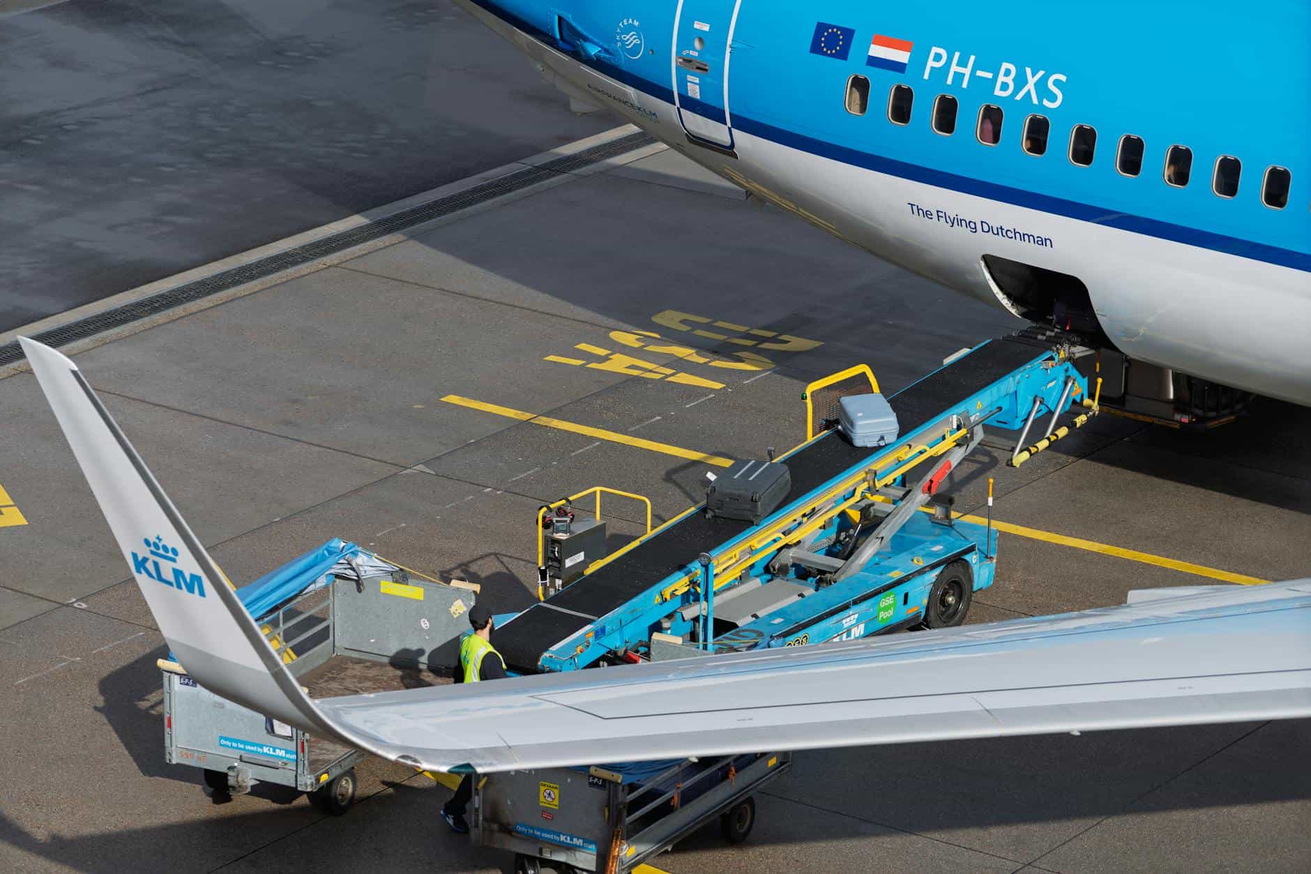 A KLM aircraft being loaded with baggage at an airport, captured on the tarmac.