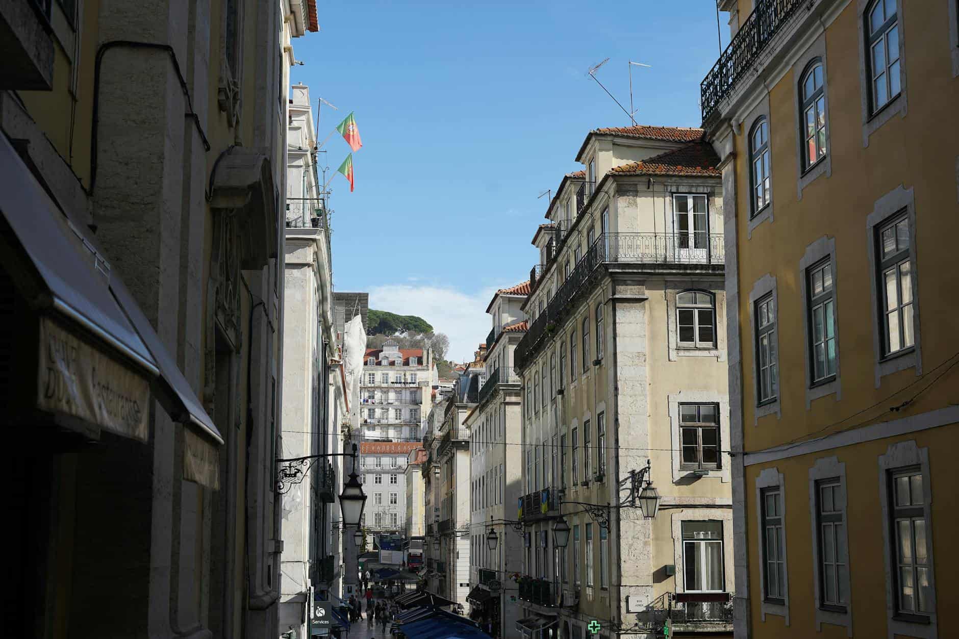 Picturesque street in Lisbon showcasing historic architecture under a bright blue sky.