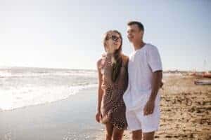 Cheerful couple enjoying a sunny day at the beach, embracing warmth and togetherness.