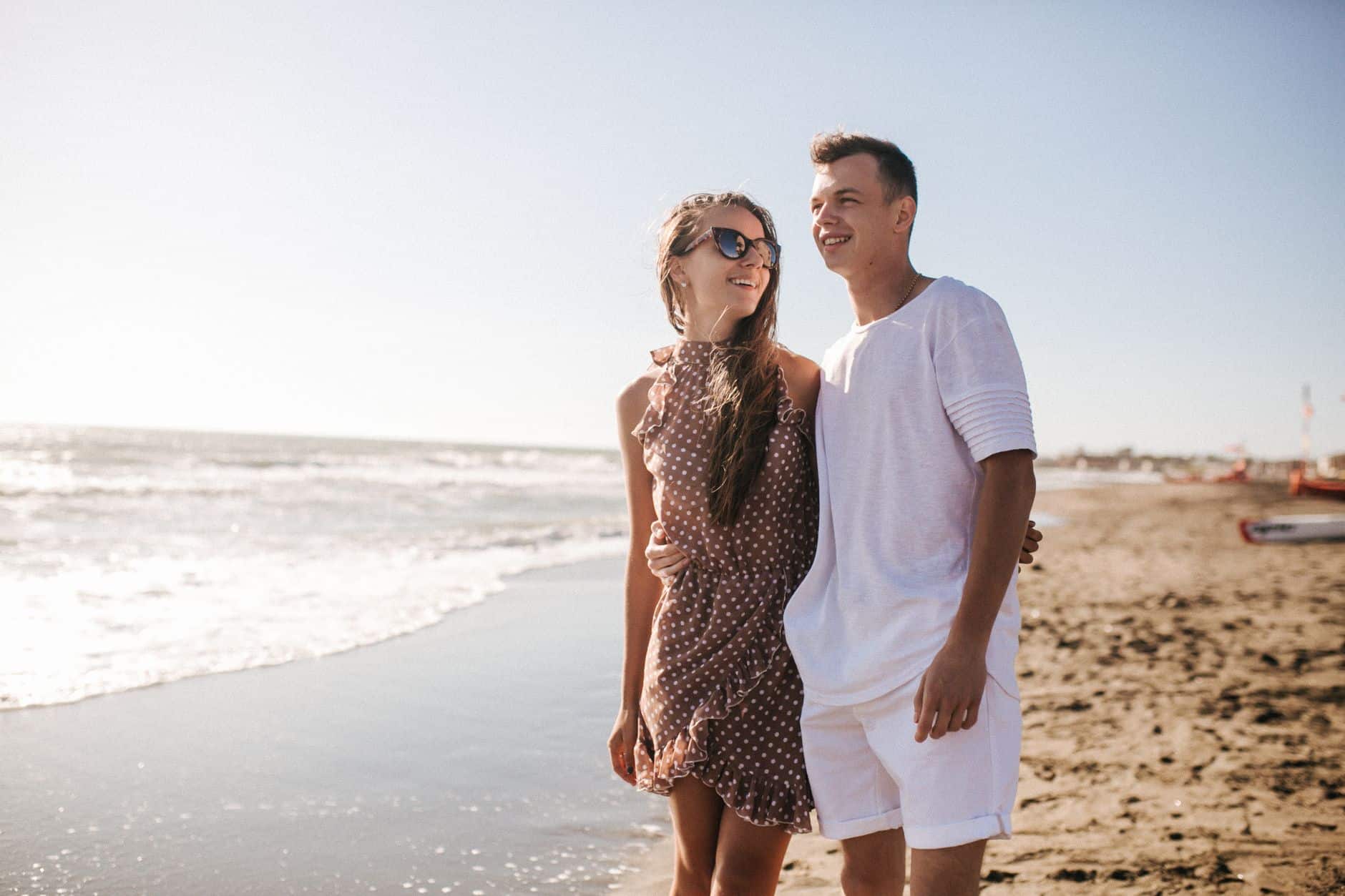 Cheerful couple enjoying a sunny day at the beach, embracing warmth and togetherness.