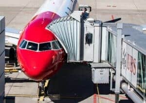 Red Airbus A320 aircraft at Zurich Airport terminal gate with boarding bridge attached.