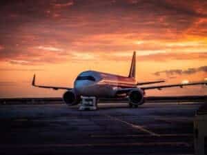 A commercial airplane stationed at Timișoara Airport with a stunning sunrise backdrop.
