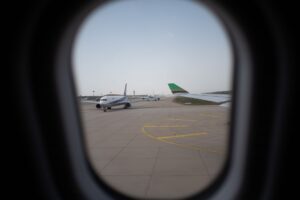 Airplane seen through a window, parked on the airport runway, capturing a travel moment.