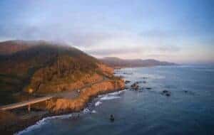 A breathtaking aerial view of the scenic Westport coastline at sunset with ocean and rugged cliffs.