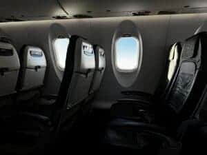 Interior of an empty airplane cabin with a bright sky visible through the window.