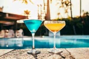 Vibrant cocktails by a poolside at sunset, perfect for summer relaxation.