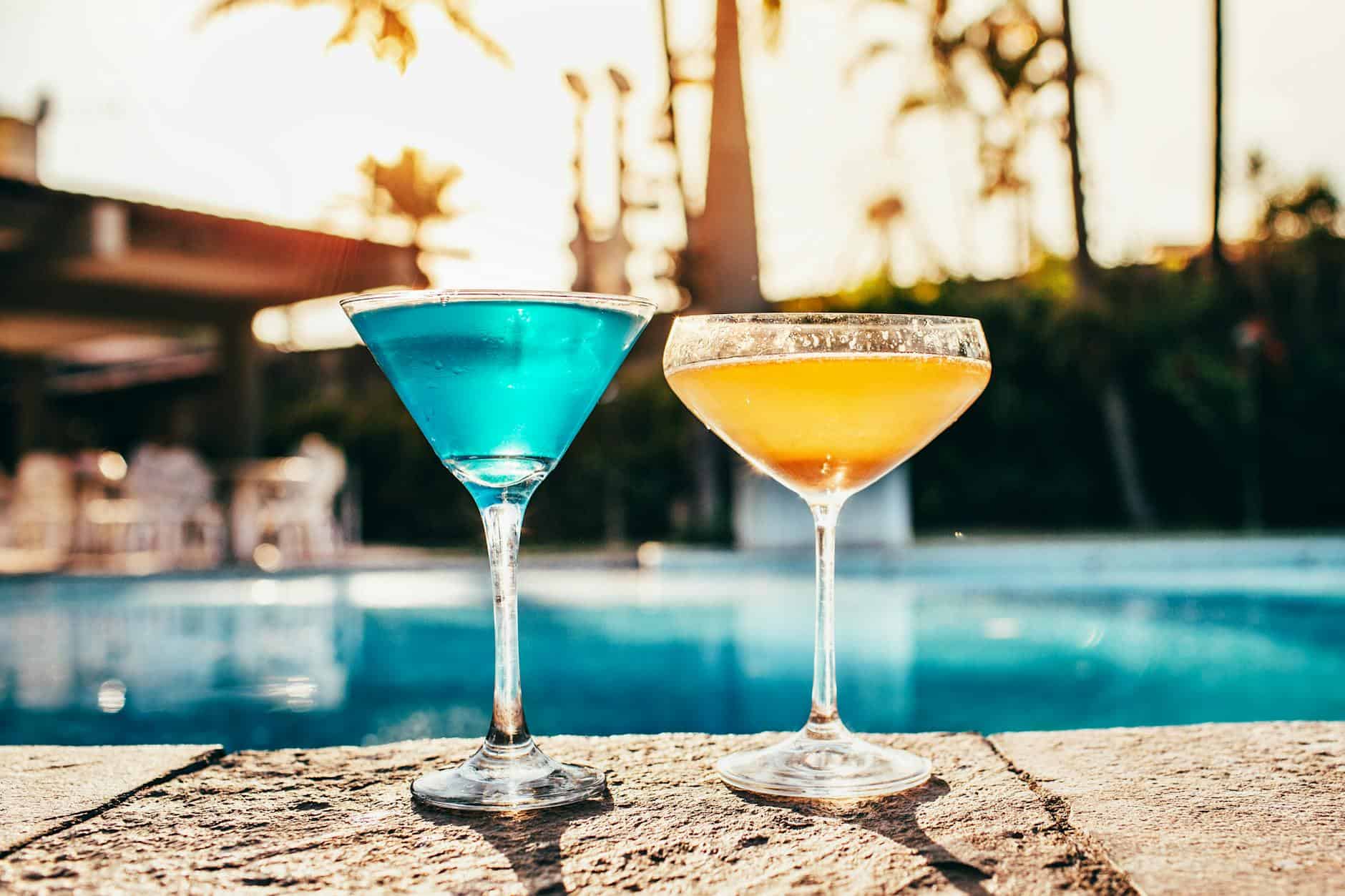 Vibrant cocktails by a poolside at sunset, perfect for summer relaxation.