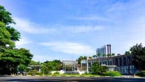 Contemporary clubhouse surrounded by lush greenery on a sunny day, suitable for resort or real estate concepts.