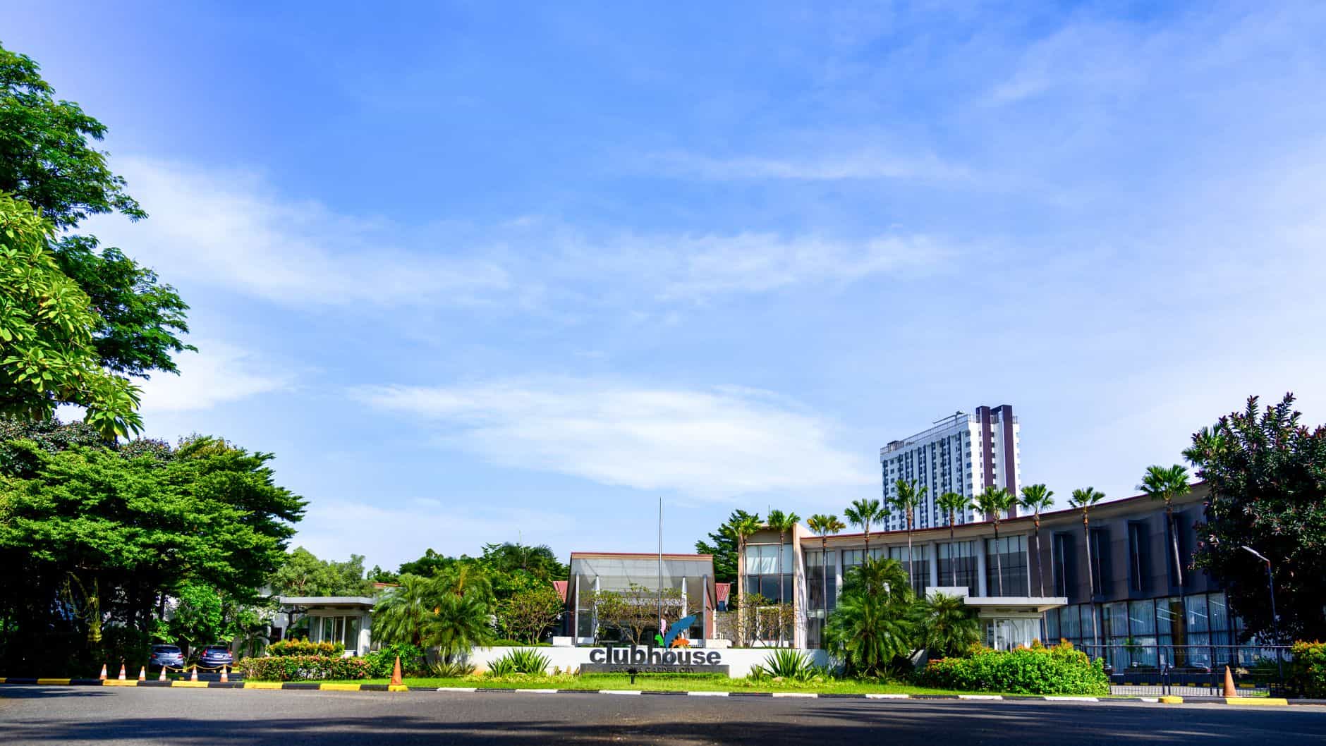 Contemporary clubhouse surrounded by lush greenery on a sunny day, suitable for resort or real estate concepts.