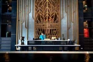 Luxurious hotel reception area with intricate design and a female receptionist at work.